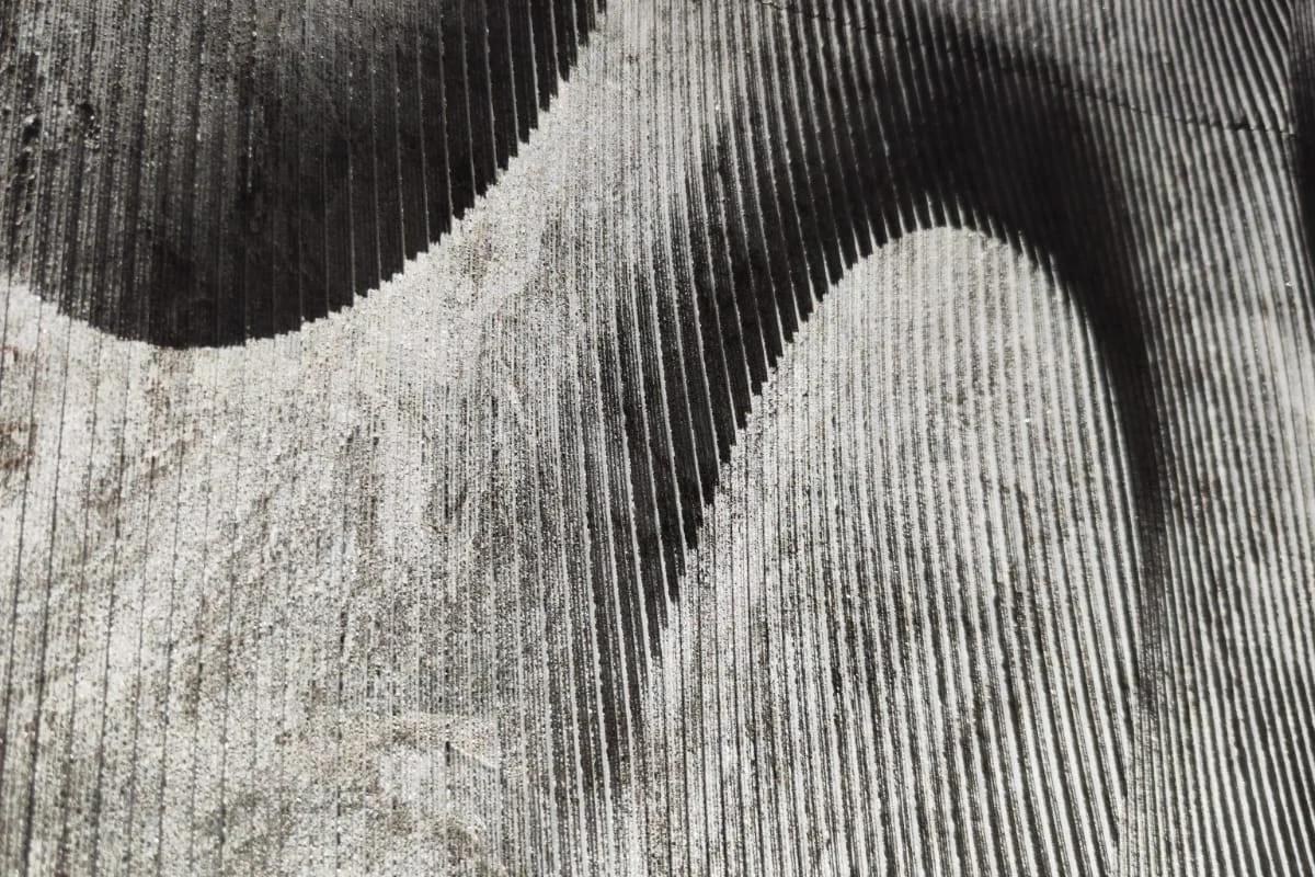 Detalhe físico Lunar Surface em pedra, com cavidades e marcas lineares de fabricação.